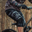 Load image into Gallery viewer, Odyssey Activewear Dark Camo Shield Shorts worn while mountain biking