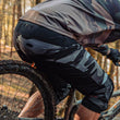 Load image into Gallery viewer, Odyssey Activewear Dark Camo Shield Shorts worn while mountain biking