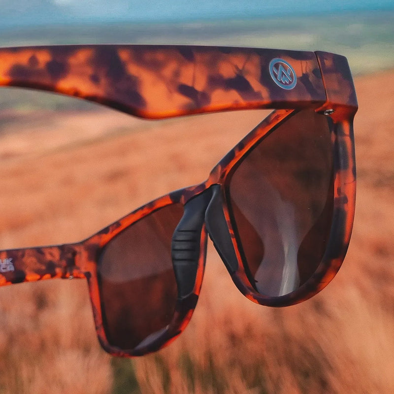 Close up photograph of Odyssey Activewear Hybrid Sunglasses against landscape scenery
