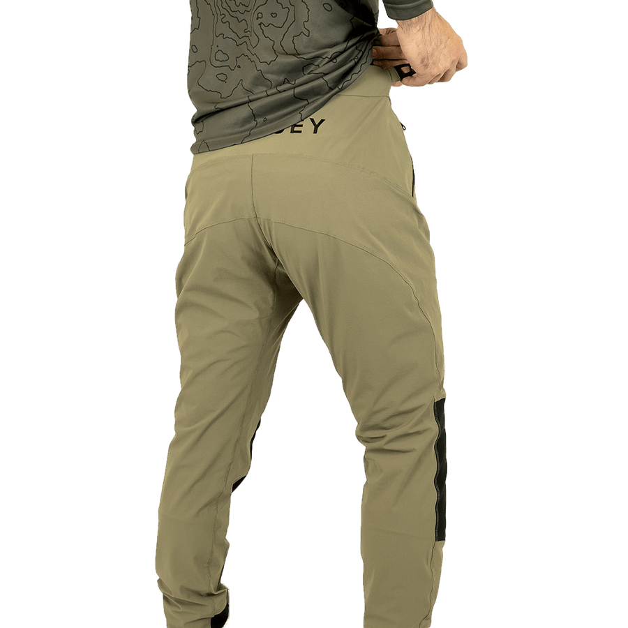 Model wearing Odyssey Activewear Shield Trousers in Khaki adjusting the elasticated waist band